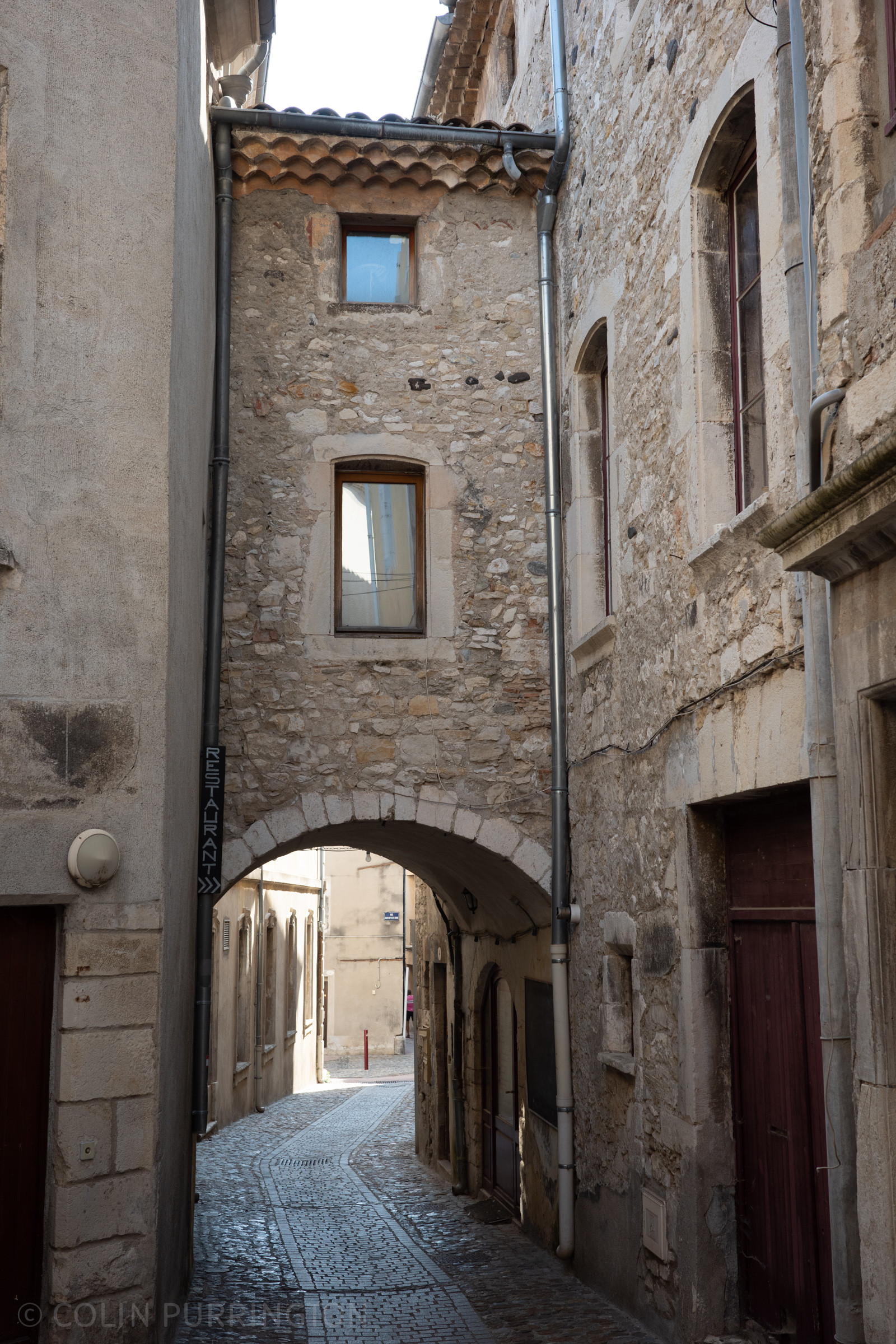 Two-story connection between buildings on the opposite side of a narrow street in a medieval city. There are windows on each level.