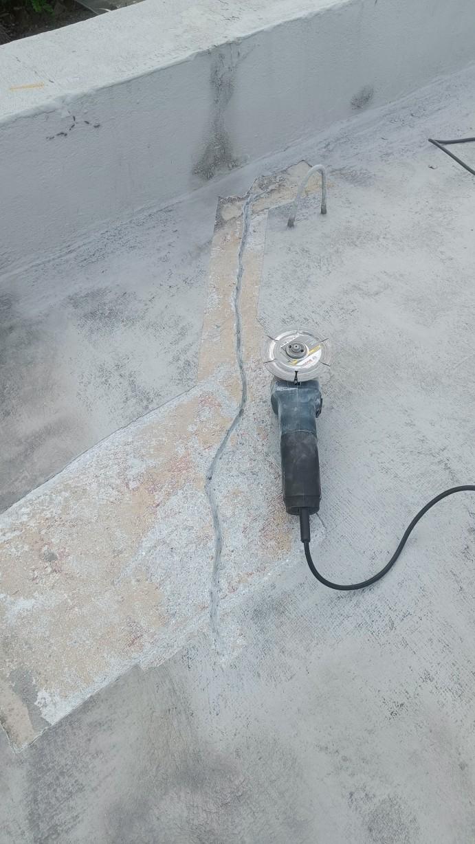 Photo of the entire length of the meandering crack after enlarging with an angle grinder (seen here to the right of the crack itself, with diamond blade for concrete attached).